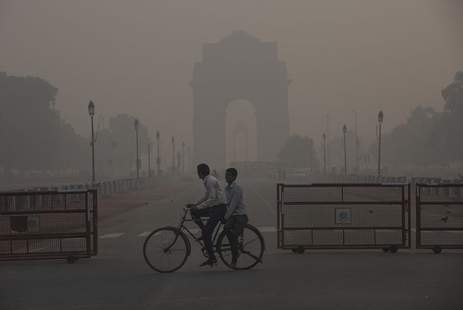 11月13日，在印度新德里，两名男子经过雾霾中的印度门。 新华社 图